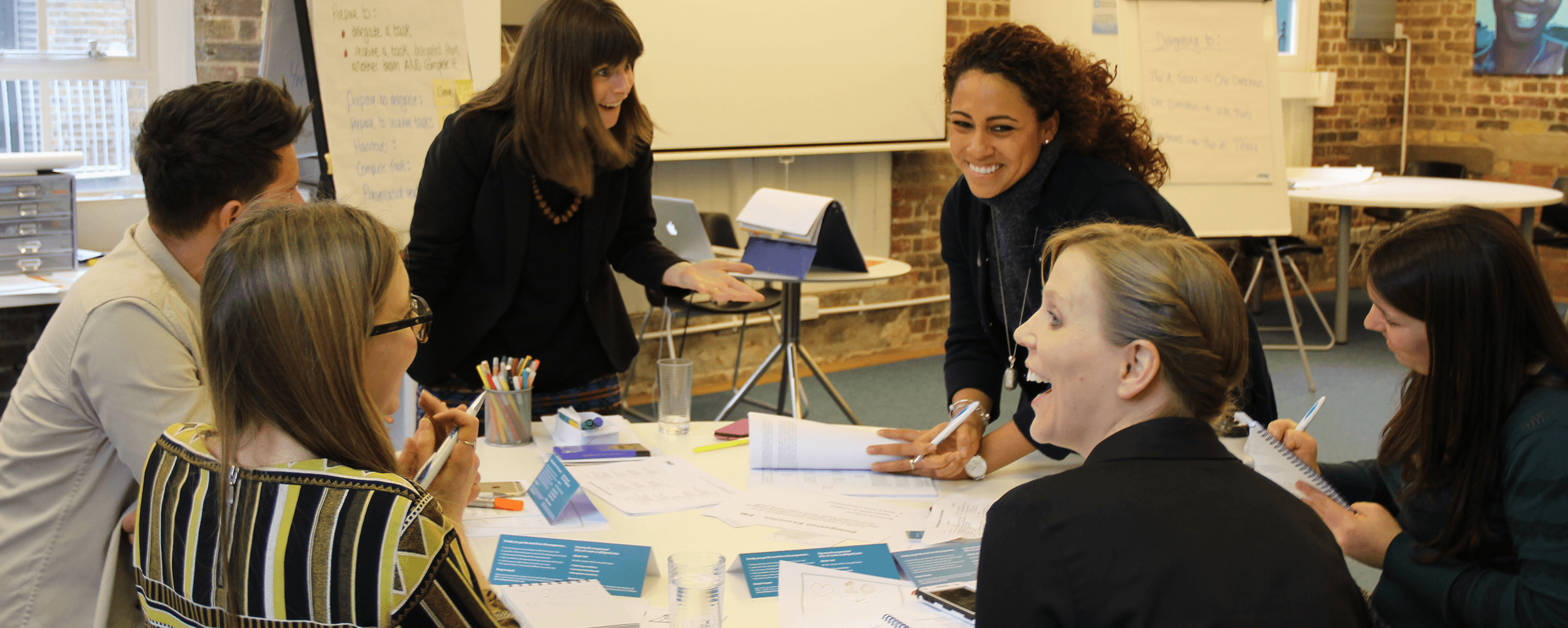 Group of people laughing around a table during a management training programme